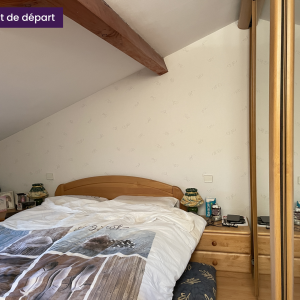 Tête de lit en bois clair avec tables de chevet et armoire miroir dans une chambre mansardée