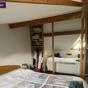 Placard ouvert sous pente avec penderie visible et lit double – chambre avant transformation