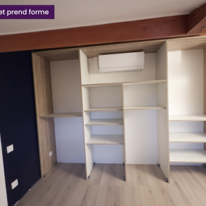 Photo d’un chantier en cours montrant la structure intérieure d’un dressing sur mesure en cours d'installation, avec étagères ouvertes et climatiseur mural déjà posé.