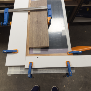 Assemblage en cours d’un encadrement de façade avec serre-joints et panneaux en bois plaqué, travail de précision en atelier