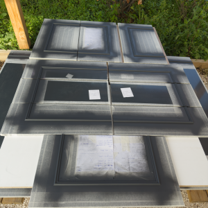Panneaux de façade noir mat en cours de peinture, installation extérieure protégée avec masquage soigné