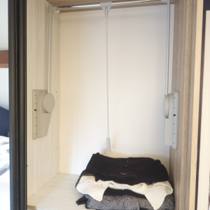 Intérieur d’un module de dressing avec penderie escamotable, en cours de remplissage.