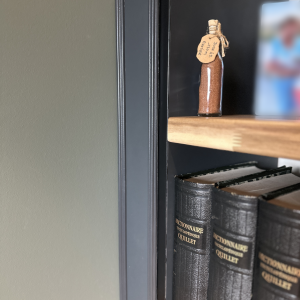 Détail d’une étagère du meuble sur mesure, avec dictionnaires anciens et petit flacon décoratif étiqueté
