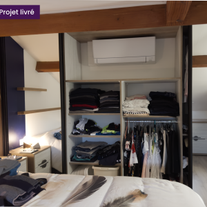 Intérieur du placard ouvert avec rangements optimisés : étagères, penderie et niche pour unité de climatisation murale.